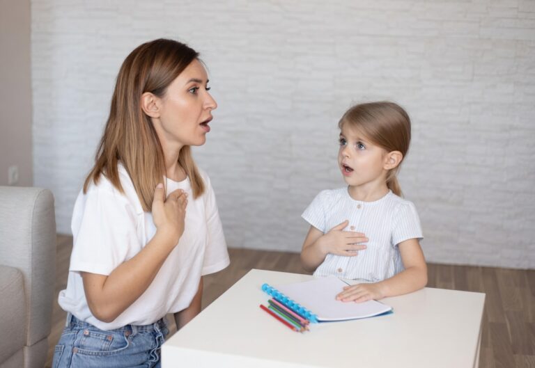 Parent and young child facing each other practising speech sounds at a table